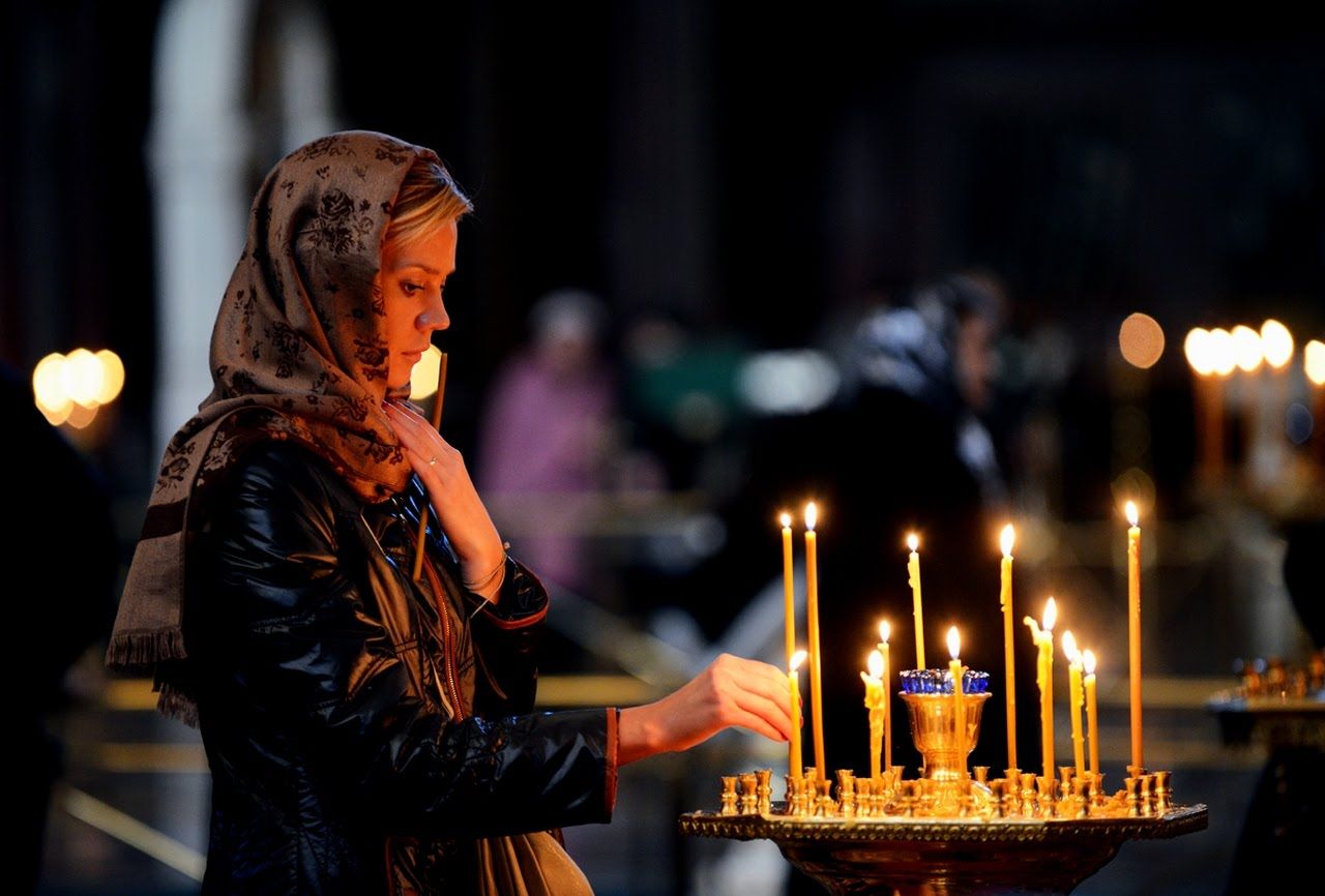 Мужчина ставит свечу. Девушка в храме. Женщина молится в храме. Девушка молится в церкви. Православная девушка.