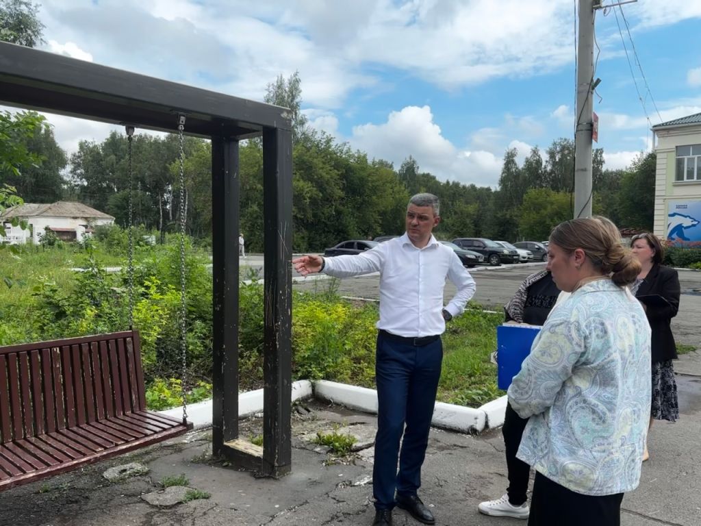 Андрей Арасланов осматривает качели на площади перед ДК в поселке Октябрьский. Глава поручил привести их в порядок ко Дню города..jpg